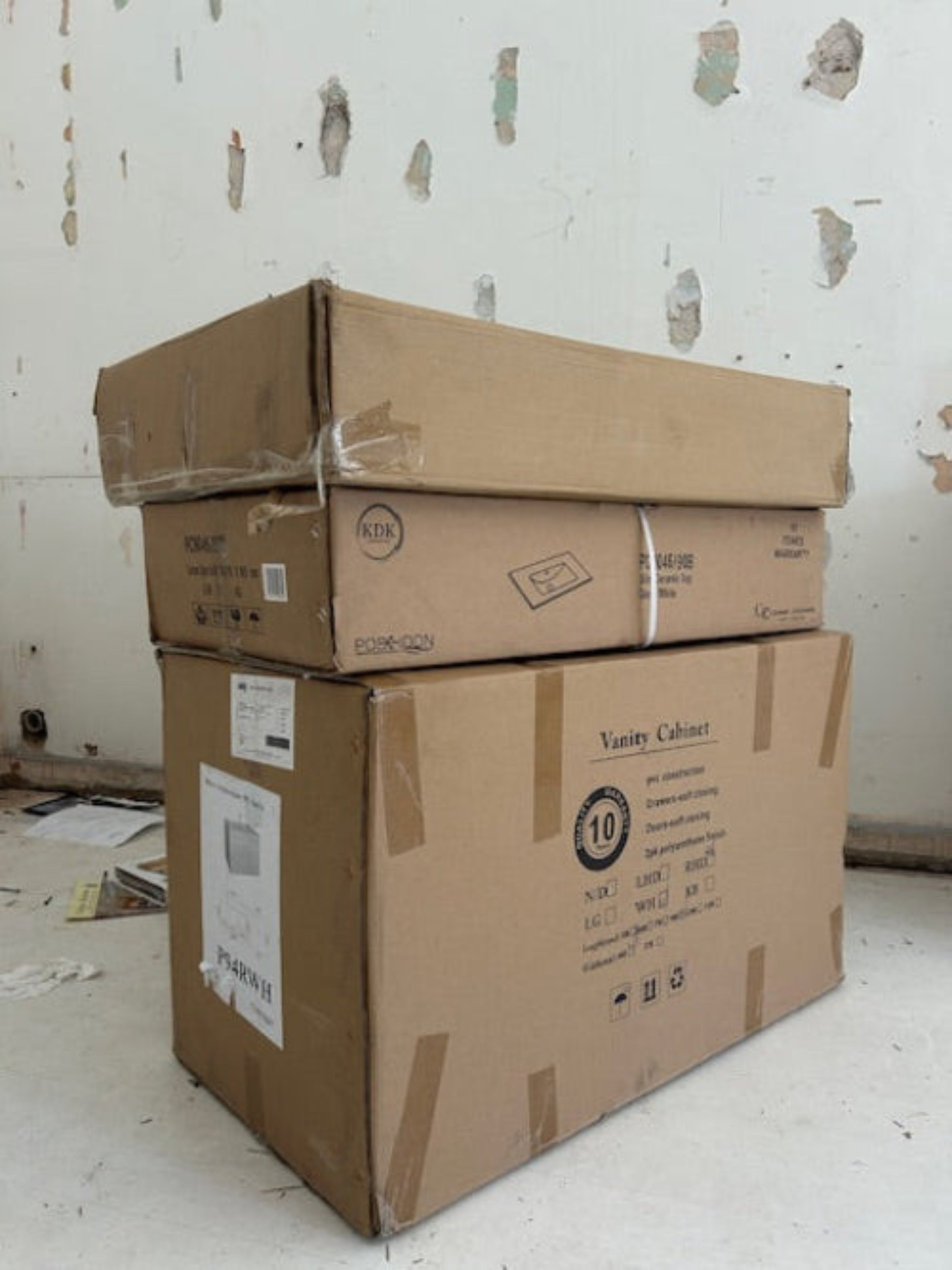 Stack of cardboard boxes on a white floor with peeling paint